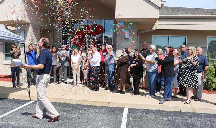 People shoot confetti into the air outside a building in celebration.