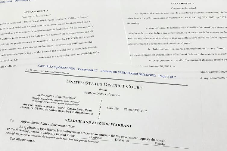 A number of court documents, with the one on top saying prominently 'Search and seizure warrant' in bold type and all capital letters.