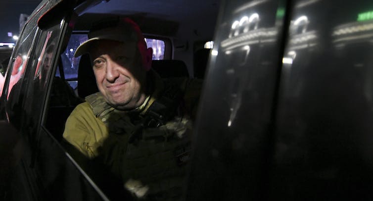 A smiling man in the back seat of a car.