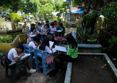 Students meet under trees as schools shelter villagers displaced by Philippine volcano