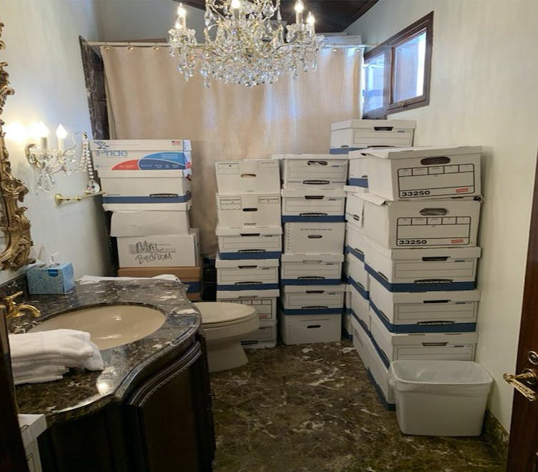 Cardboard boxes piled up in a bathroom.