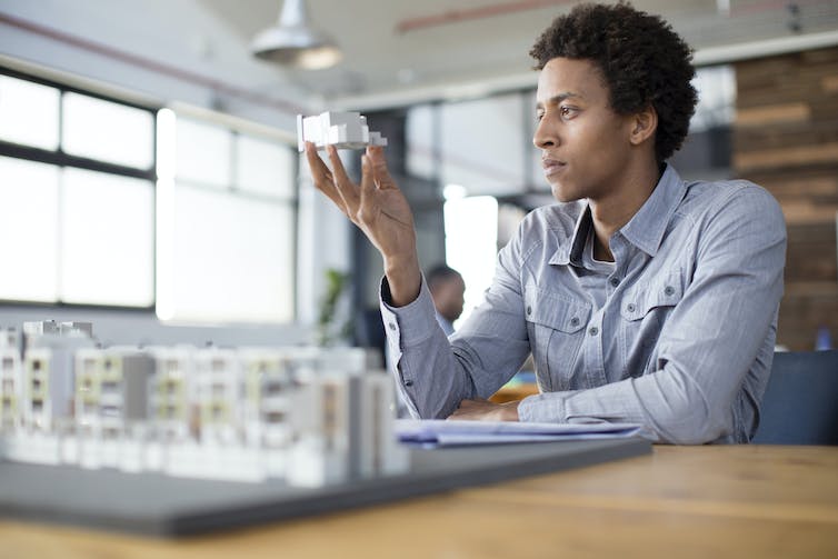 Man examines a building model in an office.