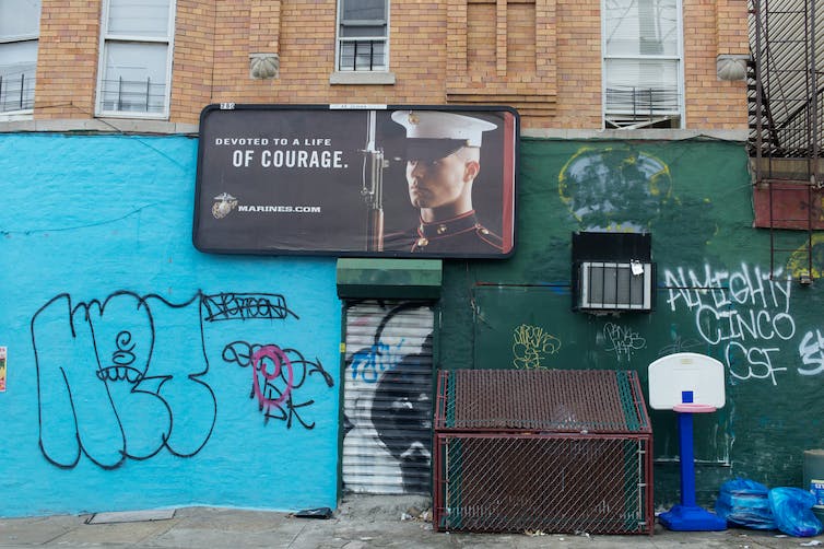 A poster of a man in a military uniform is on a wall with different types of graffiti.