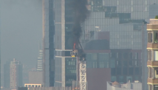 Construction crane catches fire in New York City and hits building as it crashes to street