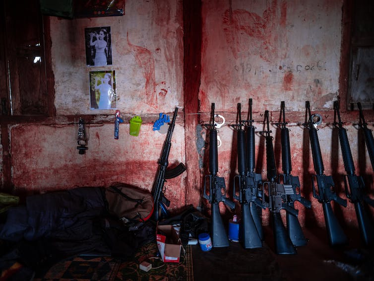 M16 assault rifles lean against a wall that appears to be blood-stained.