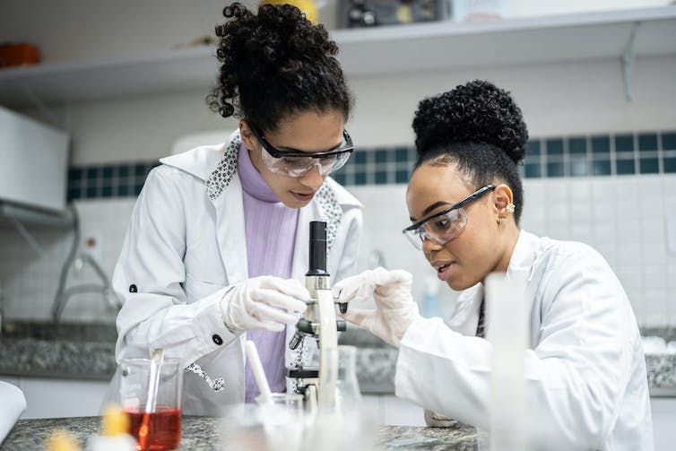 Two students are using a microscope in a laboratory.