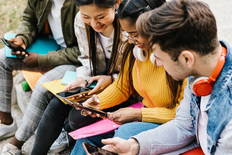 Young people sitting looking at phones