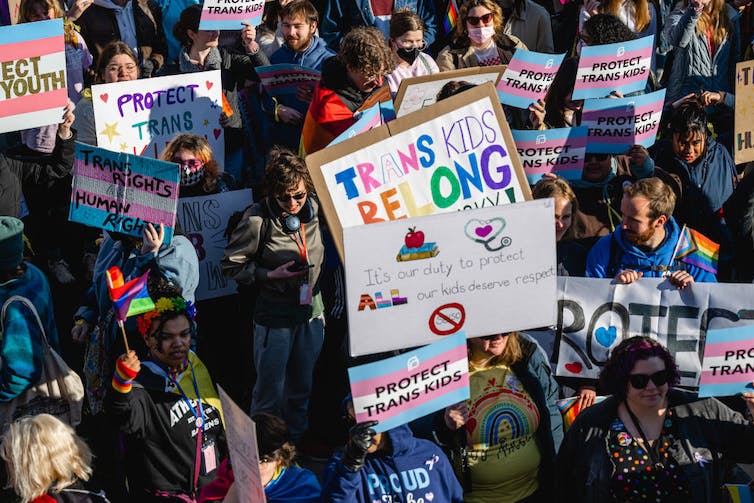 Protestors holding signs reading 'Protect trans kids' and other slogans