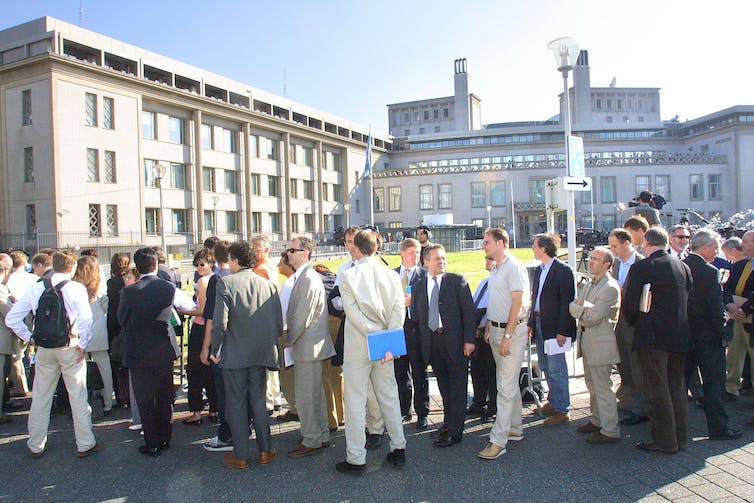 Many people lined up outside some large buildings.