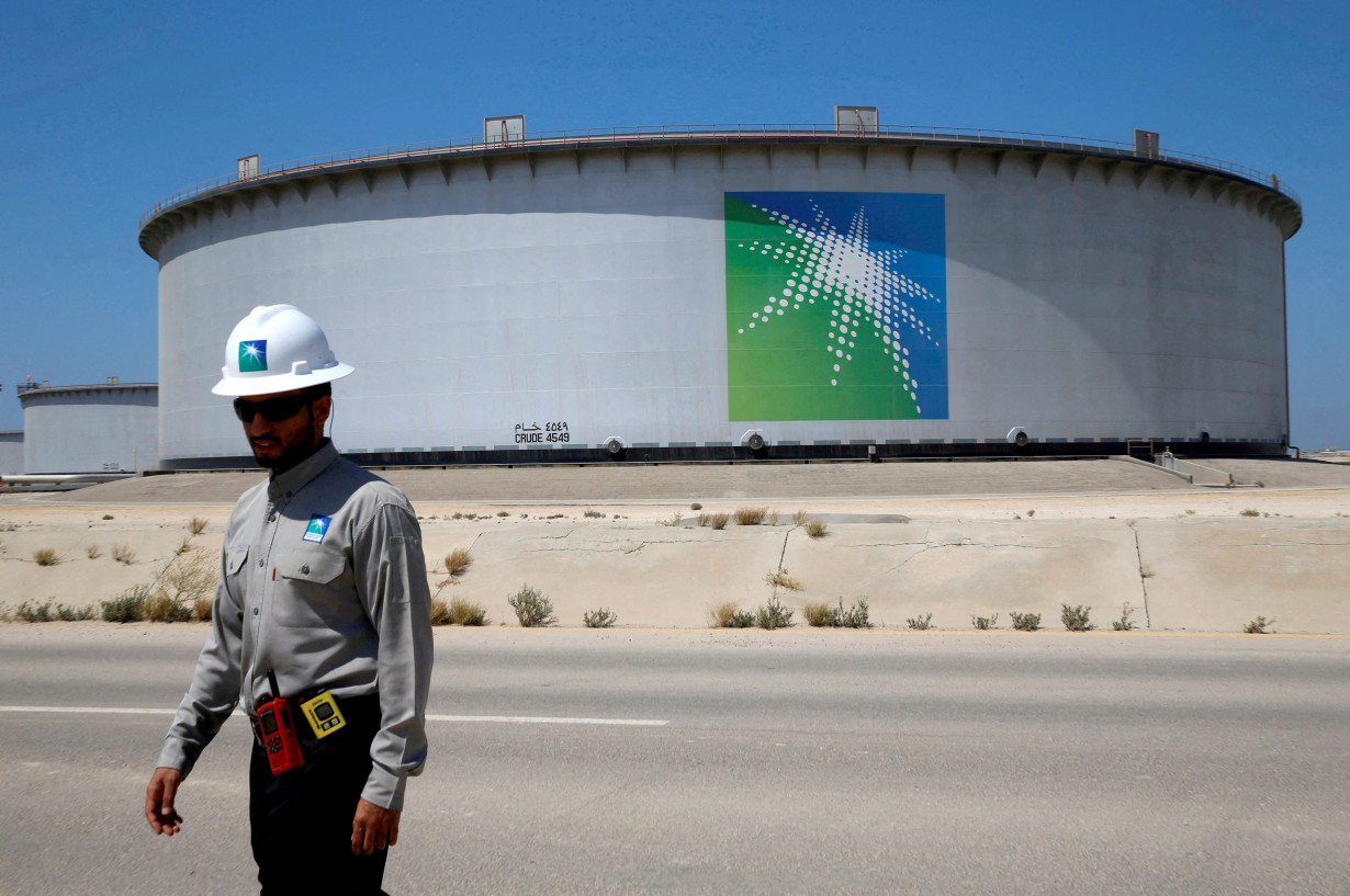 FILE PHOTO: FILE PHOTO: An Aramco employee walks near an oil tank at Saudi Aramco's Ras Tanura oil refinery and oil terminal