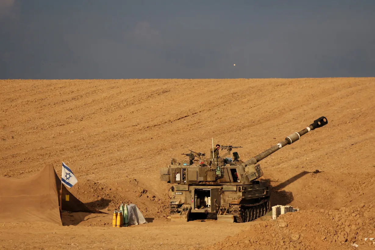 An Israeli soldier shades his eyes from the sun as he stands on self-propelled howitzer near Israel's border with the Gaza Strip, in southern Israel