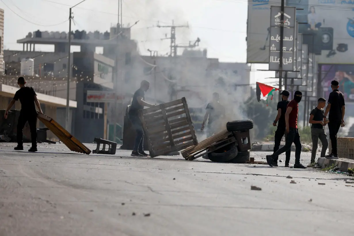 Palestinians take part in a protest following Israeli strikes on Gaza, in Nablus