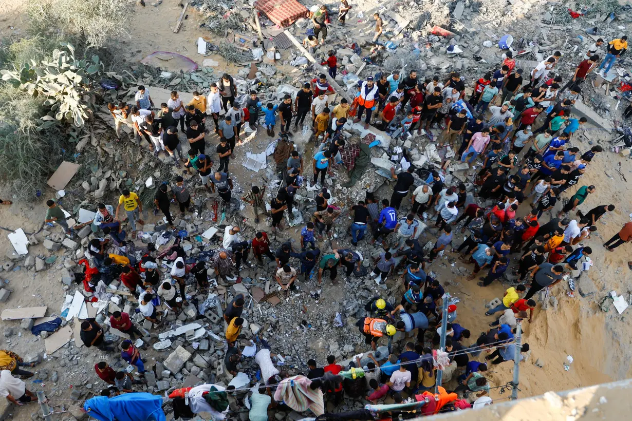 Palestinians search for casualties under the rubble of a house destroyed in Israeli strikes in Khan Younis