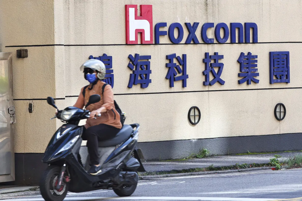 FILE PHOTO: A woman drives past the logo of Foxconn outside the company's building in Taipei