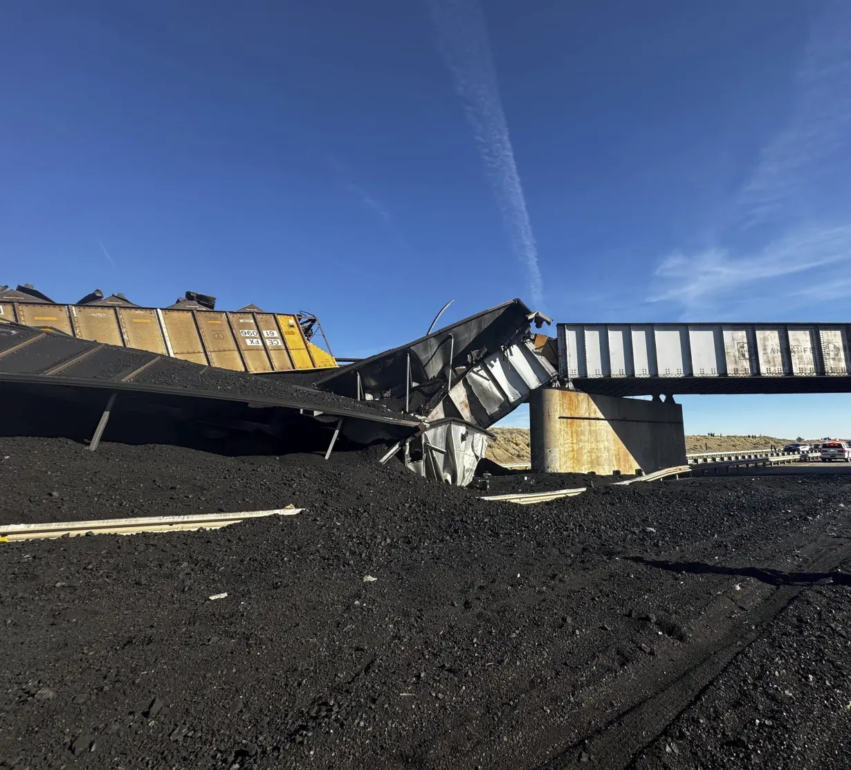 Colorado train derails, spilling train cars and coal onto a highway and trapping a semi-truck driver