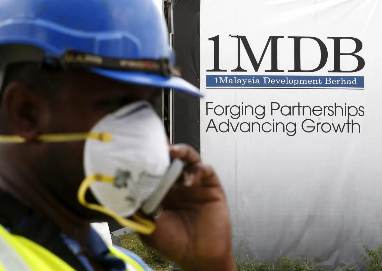 FILE PHOTO: A construction worker talks on the phone in front of a 1Malaysia Development Berhad (1MDB) billboard at the Tun Razak Exchange development in Kuala Lumpur, Malaysia