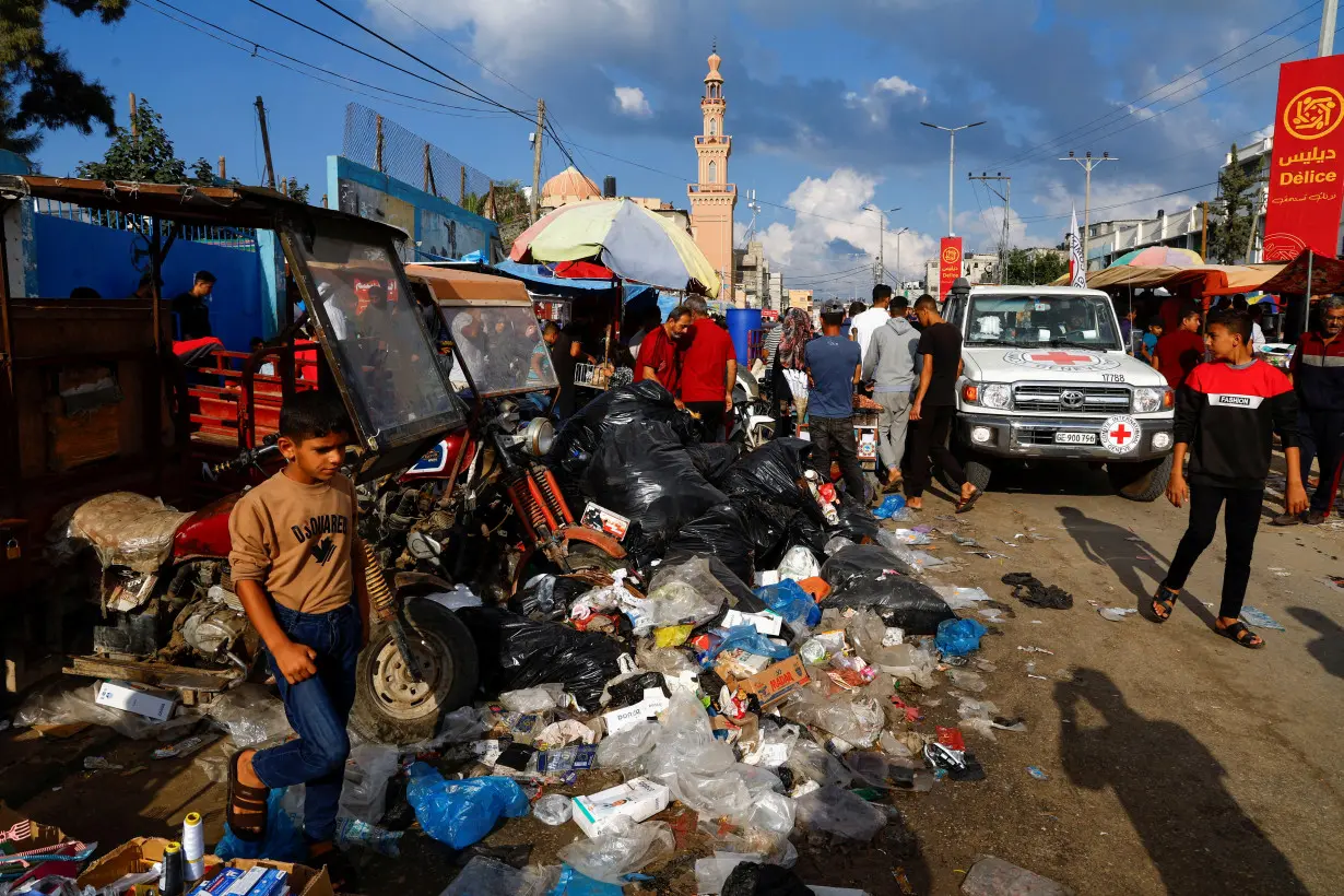 Palestinians walk past piles of garbage, amid the ongoing Israeli-Palestinian conflict in Khan Younis