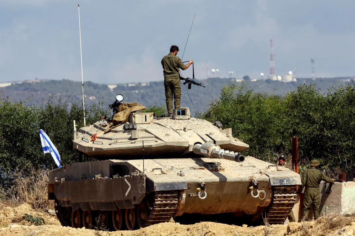 FILE PHOTO: An Israeli soldier adjusts his rifle as he stands on a tank near Israel's border with Lebanon in northern Israel