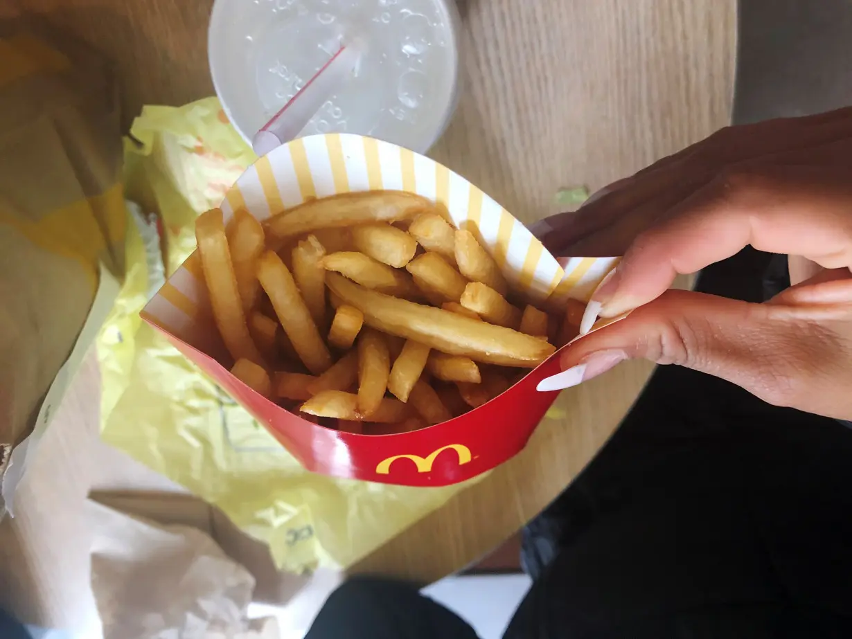 A McDonald's customer shows her french fries box at the fast-food chain McDonald's in New York