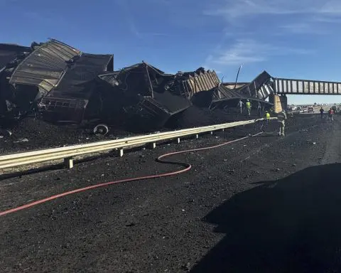 Colorado train derails, spilling train cars and coal onto a highway and trapping a semi-truck driver