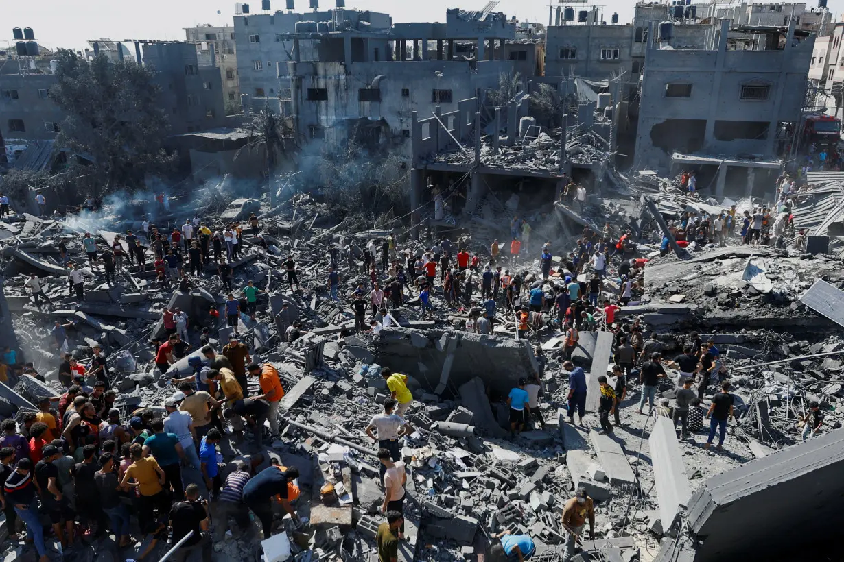 Palestinians search for casualties at the site of Israeli strikes on houses, in Khan Younis