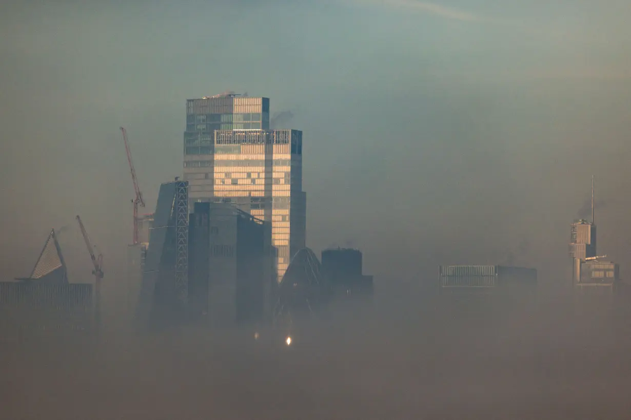 FILE PHOTO: Buildings in the city financial district are seen through fog from Canary Wharf