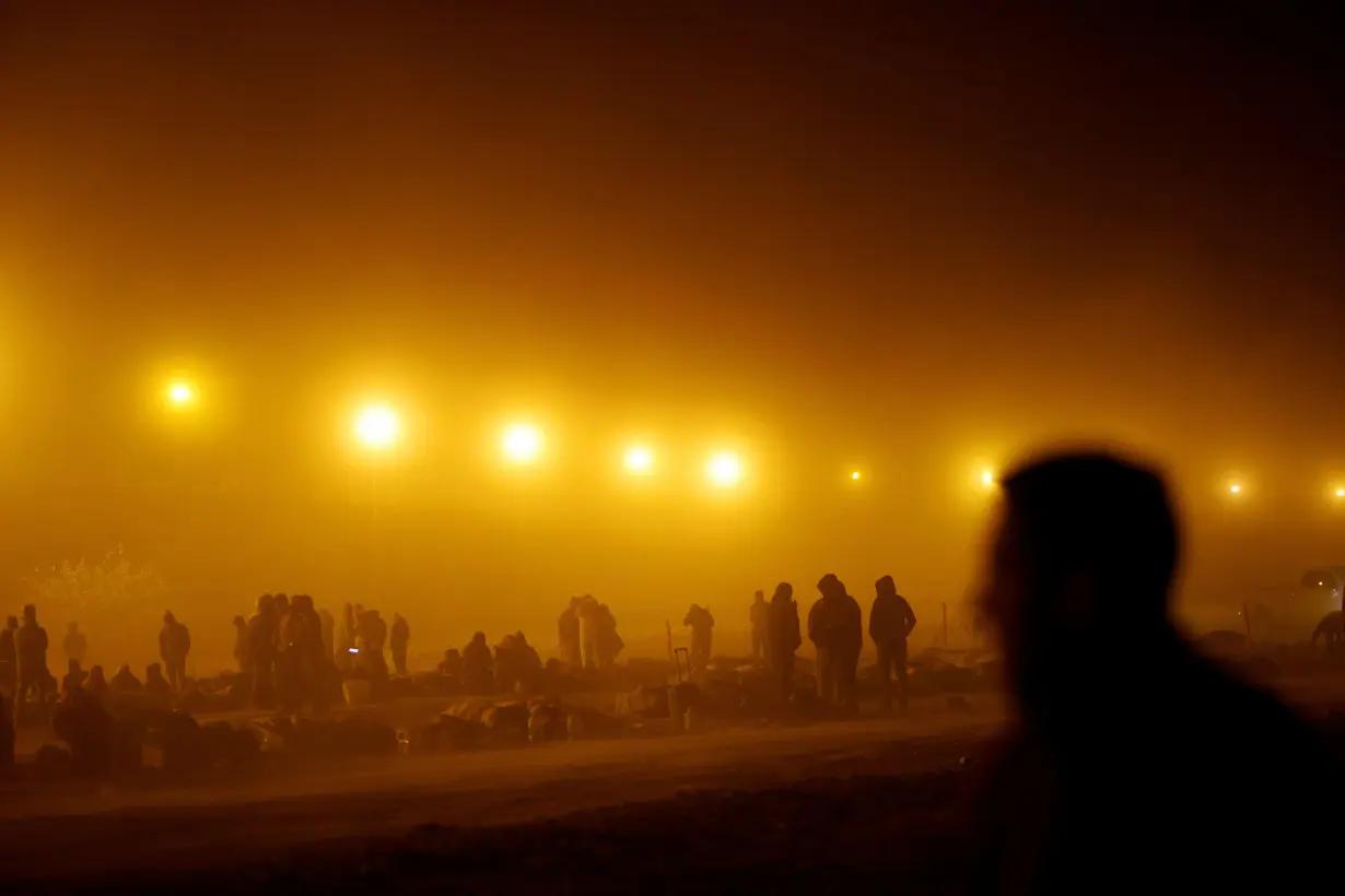 FILE PHOTO: Migrants stand near the border wall during a sandstorm after having crossed the U.S.-Mexico border