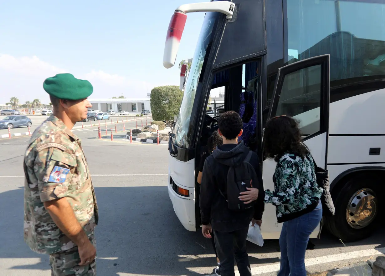 FILE PHOTO: People who were evacuated from Israel, board a bus after arriving at the Larnaca International Airport