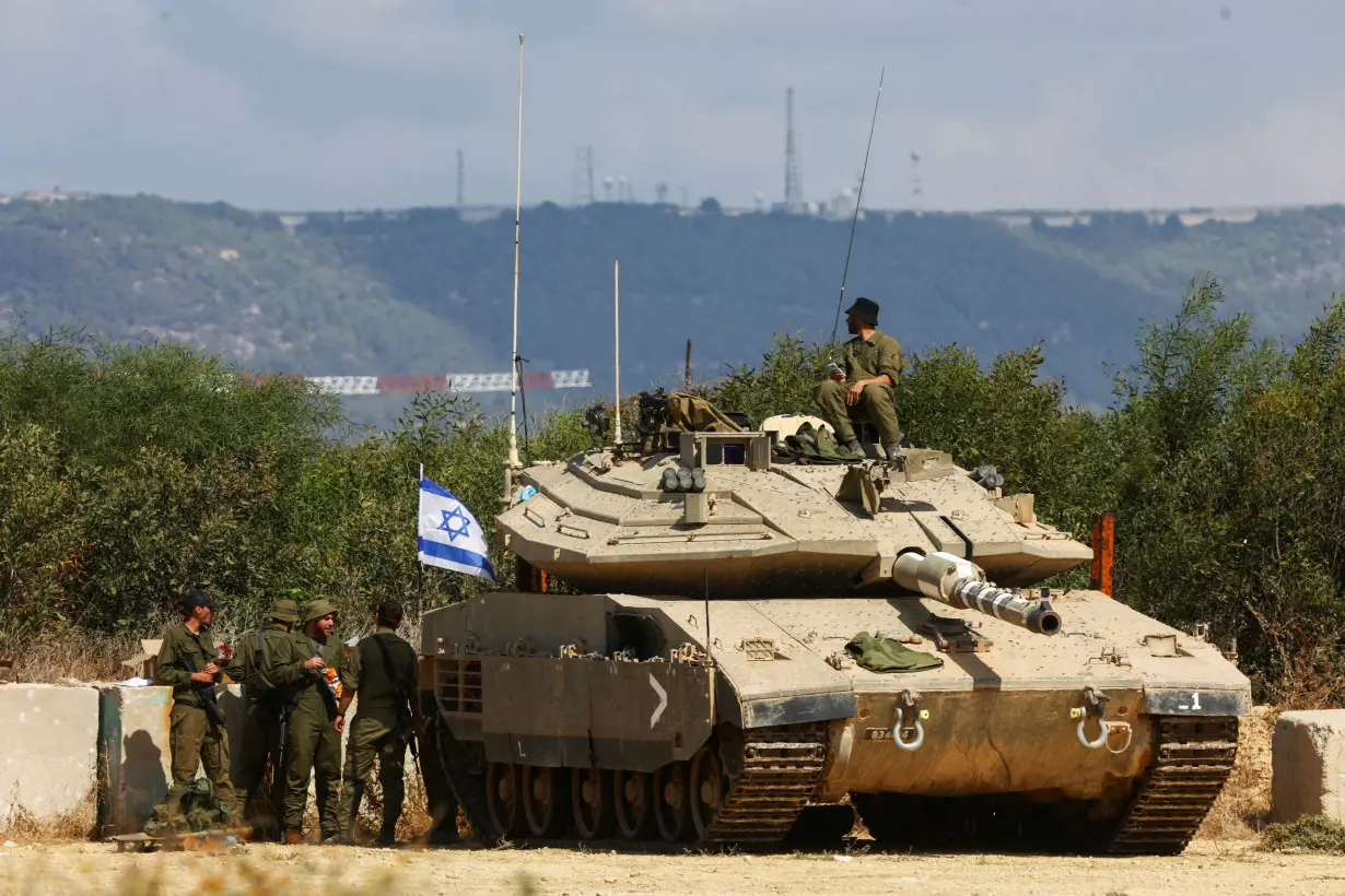 FILE PHOTO: Israeli soldiers stand near to a tank near Israel's border with Lebanon in northern Israel