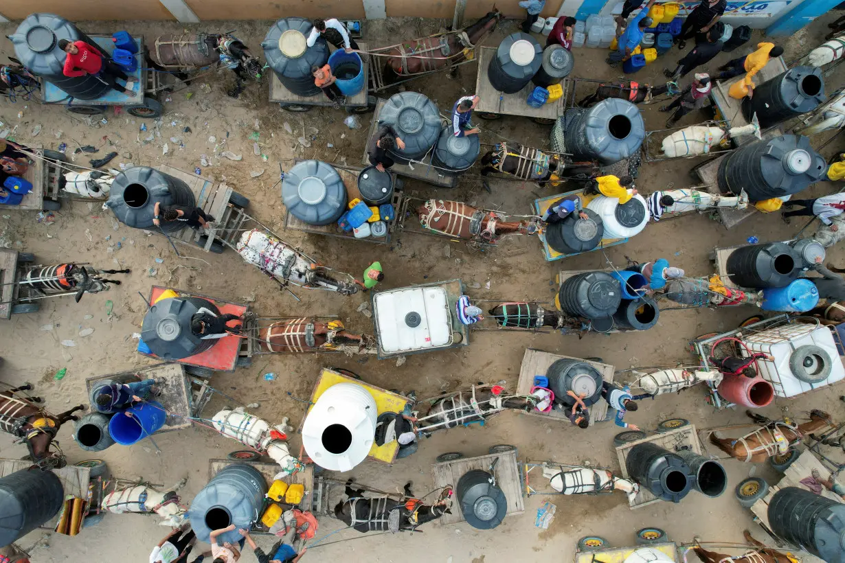 Palestinians with animal-drawn carts collect water from a water desalination plant, amid water shortages, in central Gaza Strip