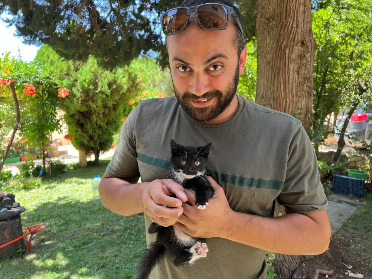 Reuters' journalist Issam Abdallah holds a kitten while posing for a picture in Saaideh, Lebanon