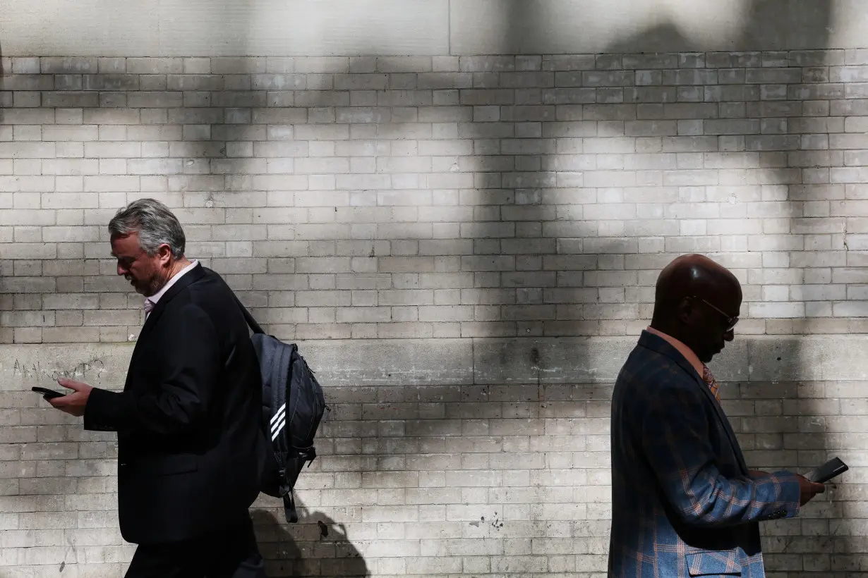 Men walk looking at their smartphones in the Midtown area of New York City