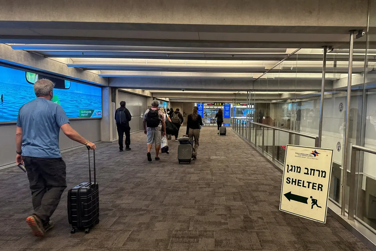 People walk next to a sign directing for Shelter after landing in Israel at the arrivals section of Ben Gurion International airport in Lod near Tel Aviv