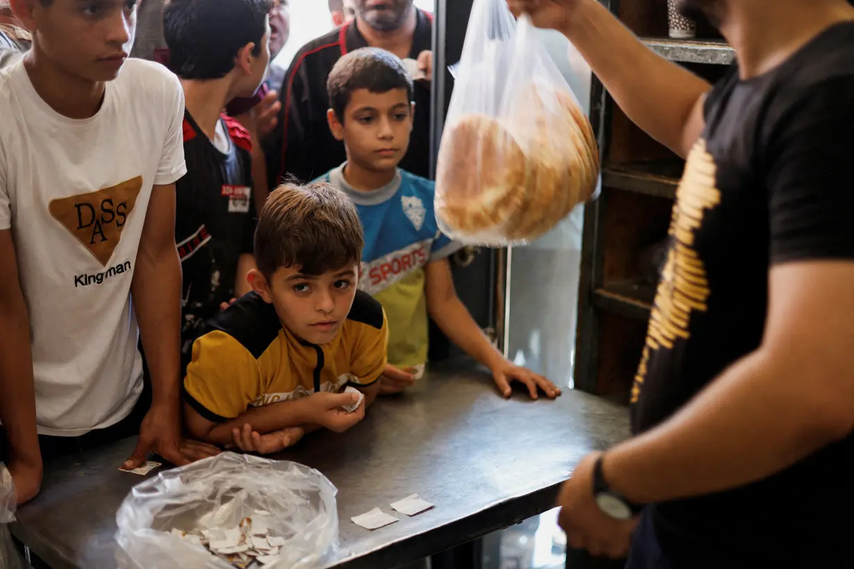 Palestinians wait to buy bread outside a bakery in Khan Younis