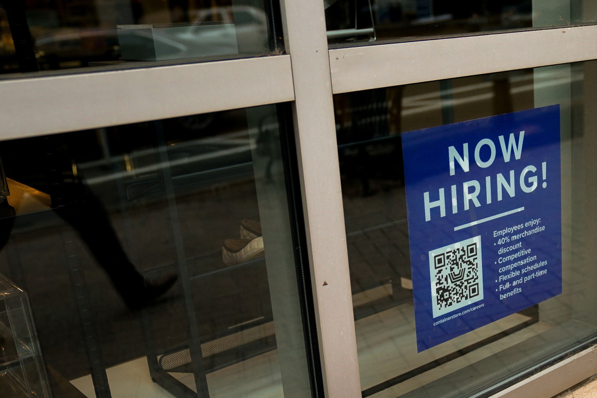 An employee hiring sign with a QR code is seen in a window of a business in Arlington