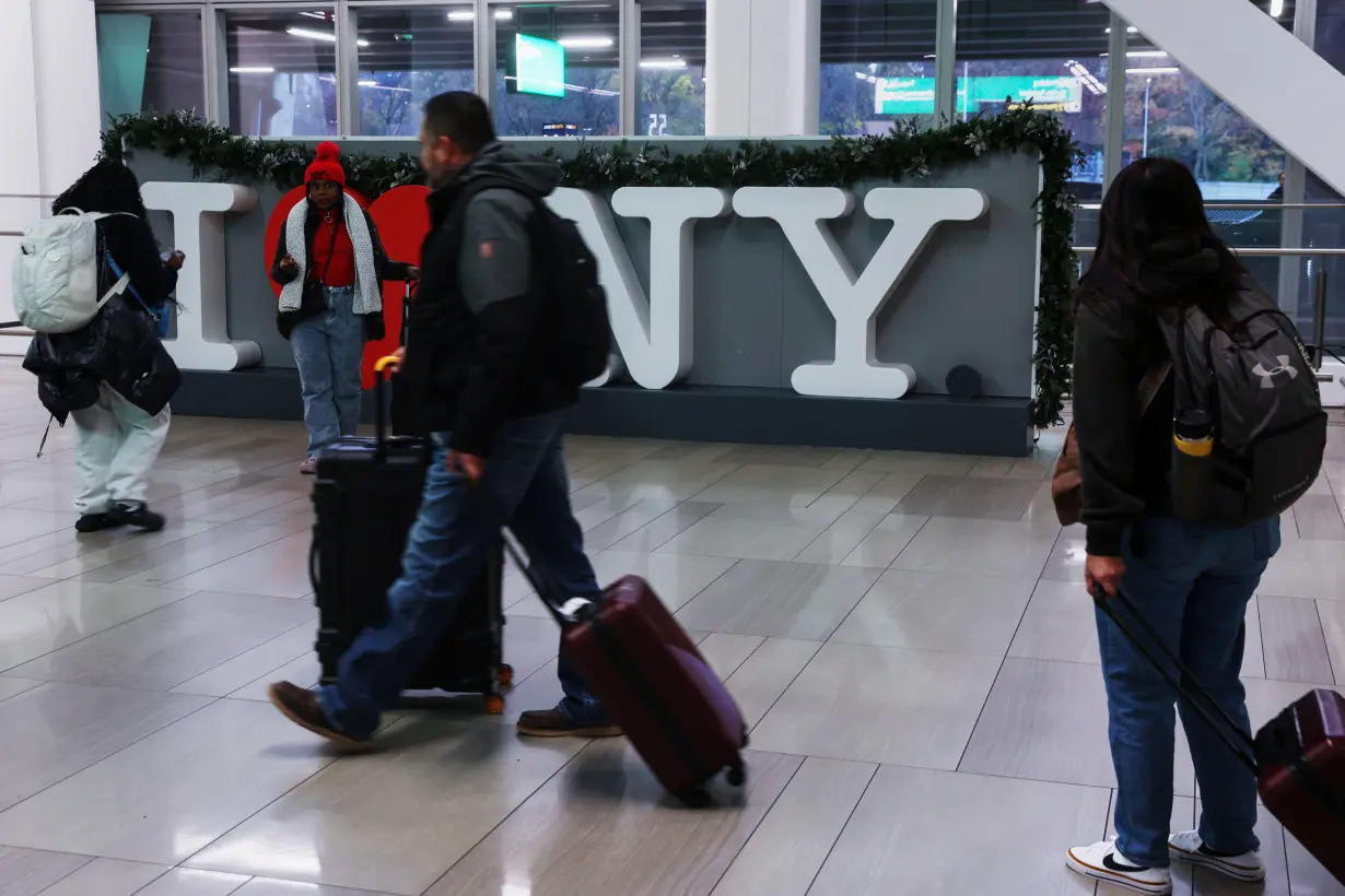 Travelers walk with luggage, as people begin to travel ahead of the Thanksgiving holiday, at LaGuardia Airport in New York City