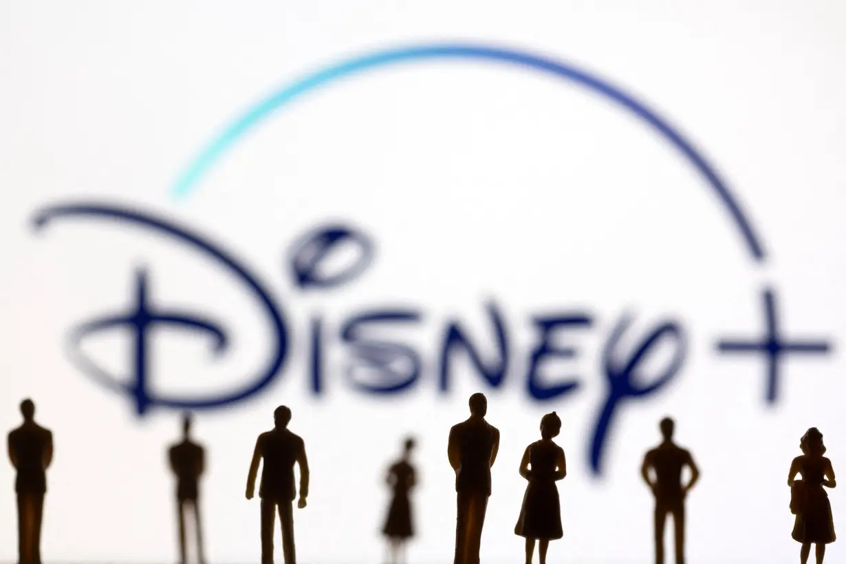 Toy figures of people are seen in front of the displayed Disney logo, in this illustration