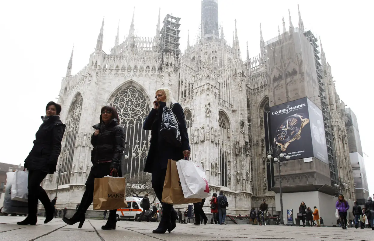 FILE PHOTO: People walk past the Duomo cathedral in downtown Milan