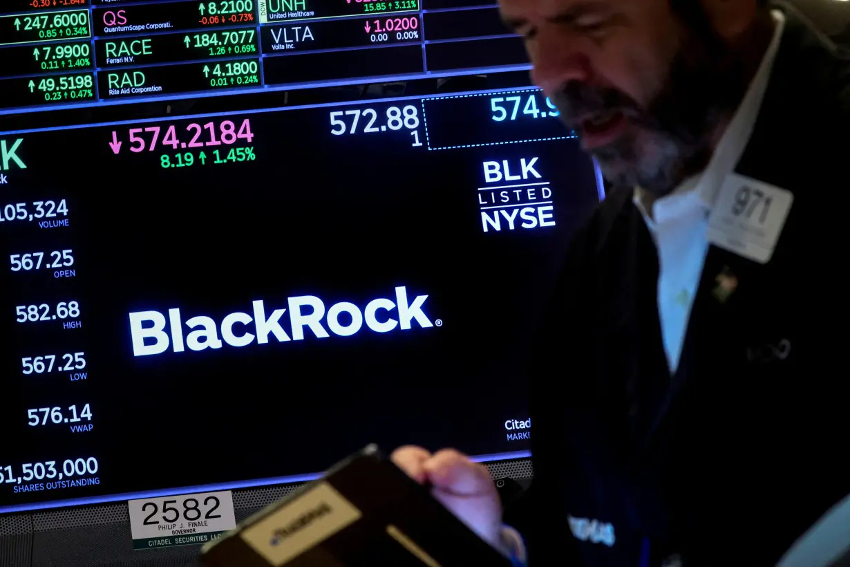 FILE PHOTO: A trader works as a screen displays the trading information for BlackRock on the floor of the NYSE in New York