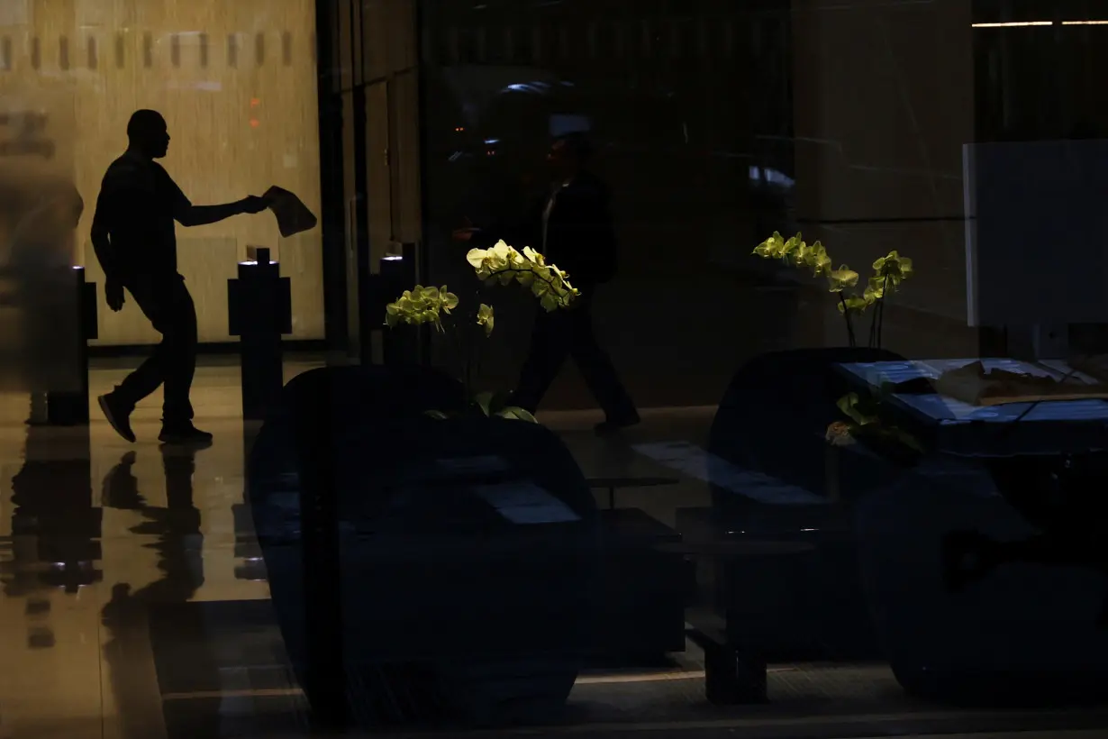 A man is seen in silhouette near flowers at an office building in the financial district of New York City,