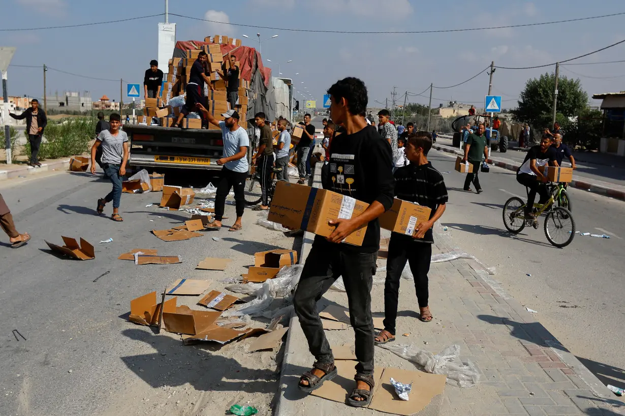 Palestinians carry aid that has fallen from a truck, in Rafah