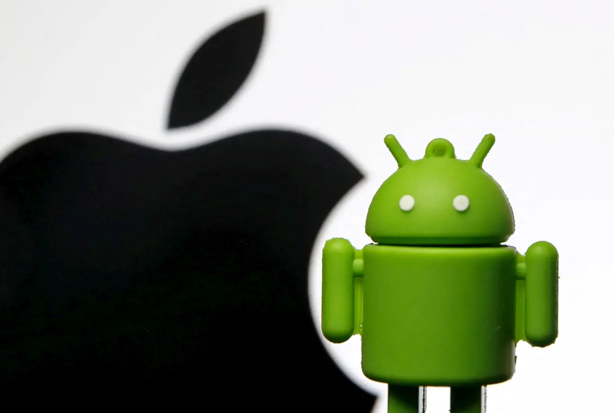 FILE PHOTO: Android mascot is seen in front of a displayed logo of Apple in this photo illustration taken in Zenica