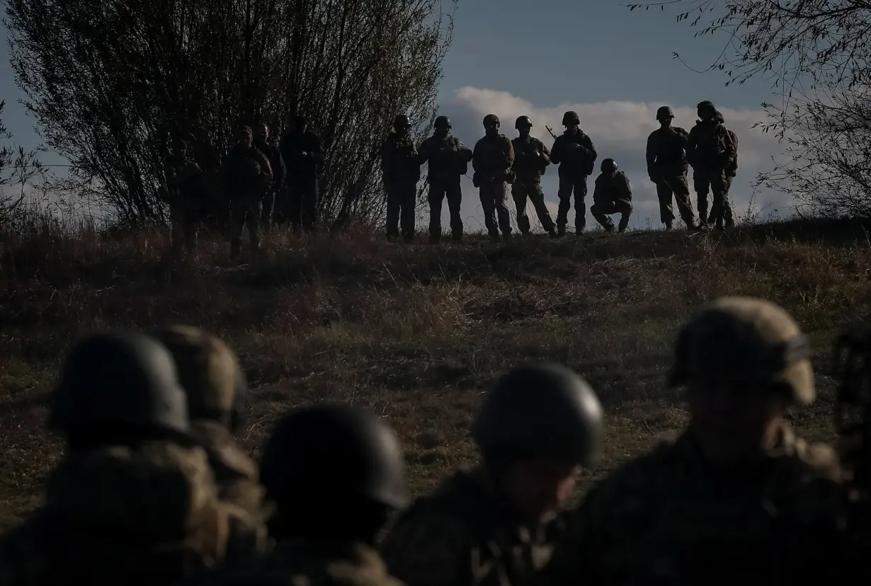 Ukrainian servicemen stand as a ferry carries their counterparts during an exercise in Chernihiv region