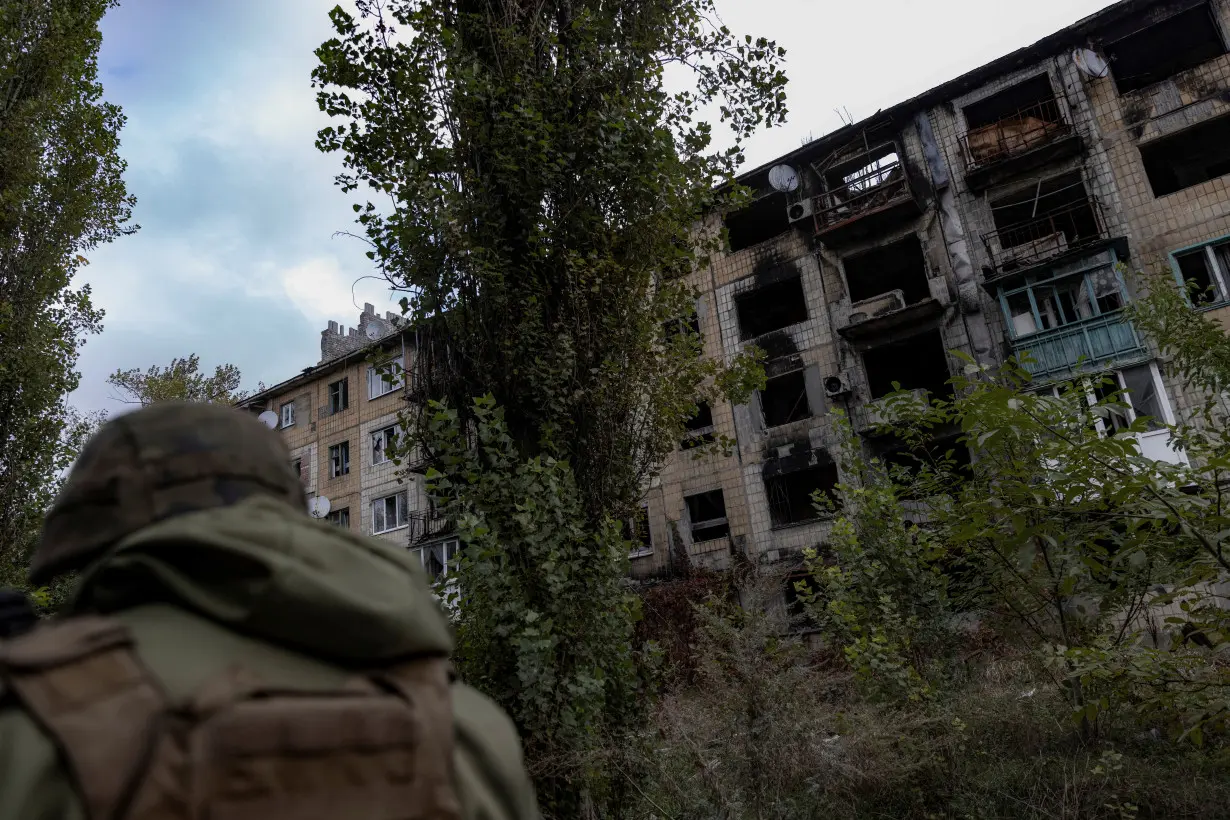 Police officer walks near a damaged residential building in Avdiivka