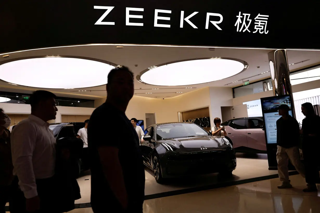 FILE PHOTO: People walk past a booth of Zeekr, Chinese automaker Geely's premium electric vehicle (EV) brand, at a shopping mall in Beijing