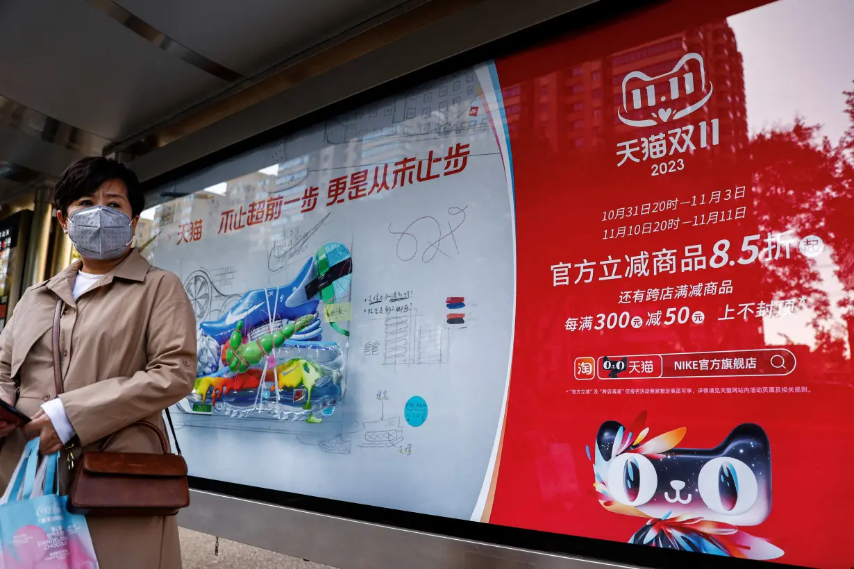 FILE PHOTO: Woman stands near an Alibaba's advertisement promoting Singles Day shopping festival in Beijing