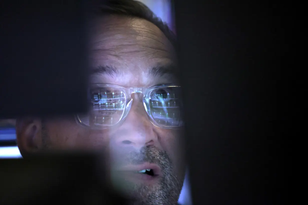 Market information is reflected in the glasses of trader as they work on the trading floor at the New York Stock Exchange (NYSE) in Manhattan, New York City