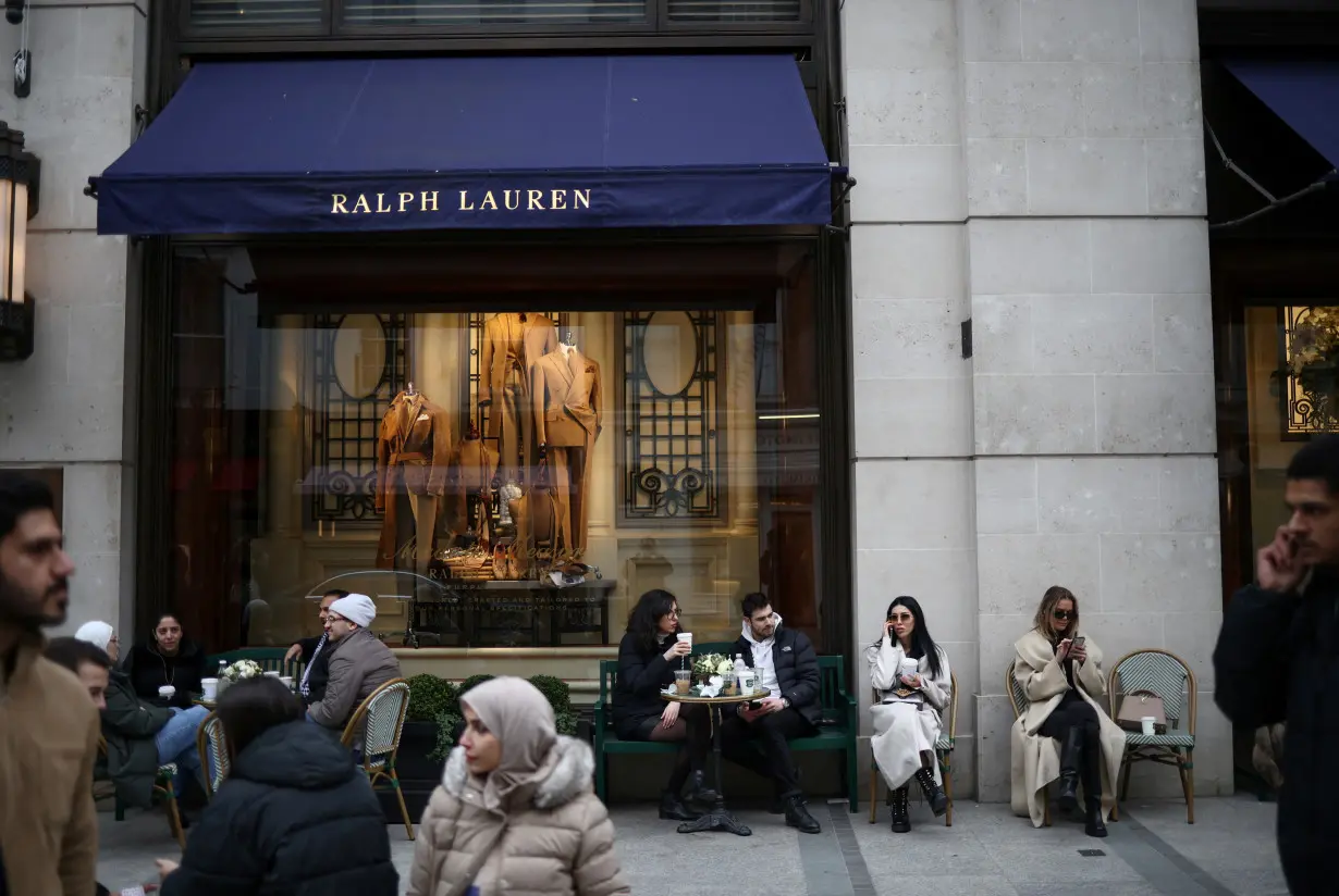 People sit outside a Ralph Lauren store on New Bond Street in London