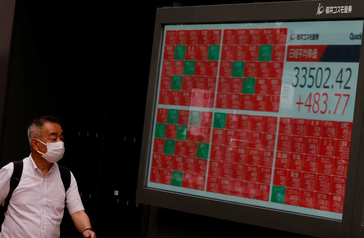 A man looks at an electric board displaying the Nikkei stock average outside a brokerage in Tokyo