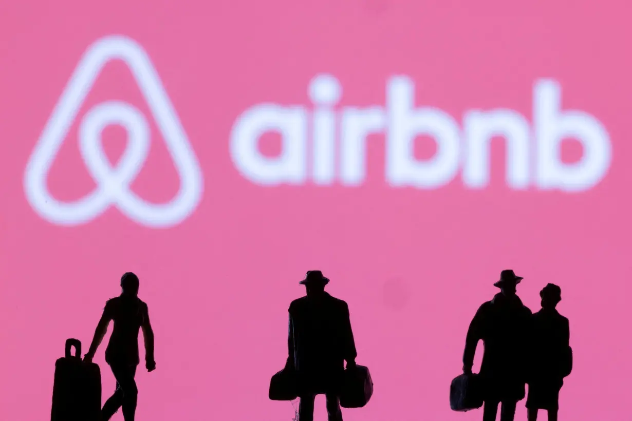 FILE PHOTO: Figurines are seen in front of displayed Airbnb logo